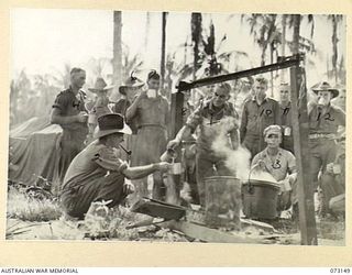 ALEXISHAFEN, NEW GUINEA. 1944-05-11. W27363 CORPORAL J. KINNELL (1), RECENTLY APPOINTED WELFARE CORPORAL, 8TH INFANTRY BRIGADE, POURS COFFEE AT A YOUNG MEN'S CHRISTIAN ASSOCIATION STALL LOCATED ..