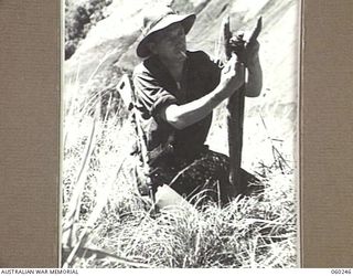 GUY'S POST, FARIA RIVER AREA, NEW GUINEA. 1943-11-06. SX3478 SERGEANT K. W. DAWSON, ACTING COMPANY SERGEANT MAJOR OF B COMPANY, 2/27TH AUSTRALIAN INFANTRY BATTALION, SETTING A BOOBY TRAP AT GUY'S ..