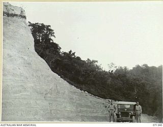 LANGEMAK BAY, NEW GUINEA, 1944-03-20. THIS CUT ON MARSH ROAD MADE BY C COMPANY, 870TH UNITED STATES AVIATION ENGINEER BATTALION MEASURING 80 FEET DEEP, 60 FEET WIDE AND 200 YARDS LONG, ALLOWED THE ..