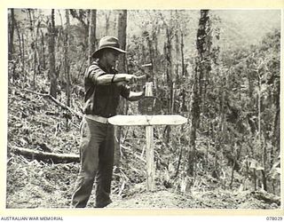 BOUGAINVILLE ISLAND. 1944-12-30. QX37473 STAFF SERGEANT R.C. KEATES, 25TH INFANTRY BATTALION ERECTING A CROSS OVER THE GRAVE OF ONE OF HIS COMPANIONS, QX59372 PRIVATE E.C.H. STEPHSON WHO WAS KILLED ..