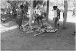 Ambaiat: distribution of pork from pig killed for damaging garden, owner of pig, Ausander (in shirt) supervises, woman awaits share