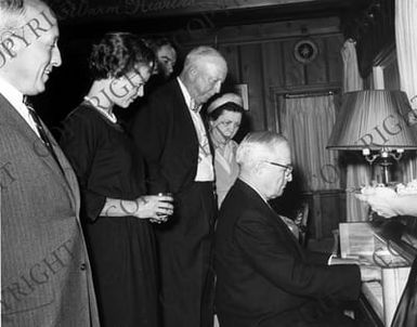 Former President Harry S. Truman at the home of Edwin Pauley, playing the piano for unidentified visitors