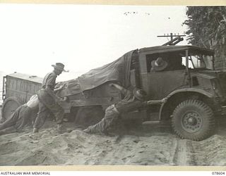 BOUGAINVILLE ISLAND. 1945-01-24. A 15 CWT TRUCK OF HEADQUARTERS, 7TH INFANTRY BRIGADE BOGGED IN SAND ON THE BEACH ROAD. NOTE THIS TRUCK IS TOWING A JAPANESE ELECTRICITY GENERATOR ABANDONED BY THE ..