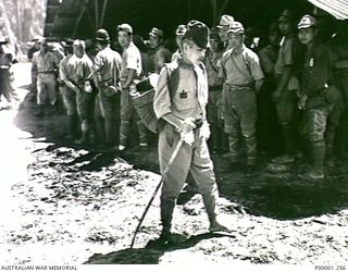 THE SOLOMON ISLANDS, 1945-09. JAPANESE TROOPS FROM NAURU ISLAND STANDING OUTSIDE A BUILDING AT THEIR INTERNMENT CAMP ON BOUGAINVILLE ISLAND. (RNZAF OFFICIAL PHOTOGRAPH.)