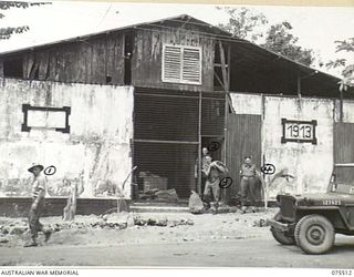 MADANG, NEW GUINEA. 1944-08-25. THIS OLD BUILDING THE PRE- WAR CIVILIAN GAOL, IS NOW THE OFFICES OF THE POSTAL, PAY AND QUARTERMASTER SECTIONS OF THE 2/11TH GENERAL HOSPITAL. IDENTIFIED PERSONNEL ..