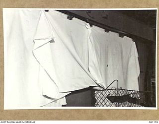 17 MILE, PORT MORESBY AREA, NEW GUINEA. 1943-12-04. THIS DRYING MACHINE OF THE 9TH AUSTRALIAN DIVISION MOBILE LAUNDRY CARRIES THE ARTICLES THROUGH A HEATED CHAMBER AND RELEASES THEM AUTOMATICALLY ..