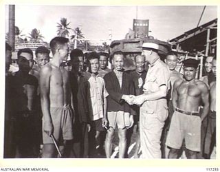 NAURU ISLAND, 1945-09-13. MR W.V. BOTT, CHIEF ENGINEER OF THE BRITISH PHOSPHATE COMMISSION, BEING GREETED BY CHINESE AND NAURUAN LABOURERS ON HIS RETURN TO THE ISLAND