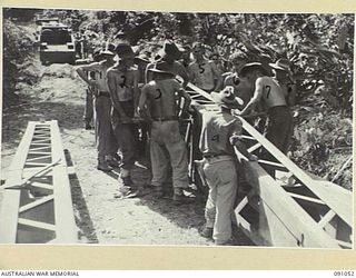 BOUGAINVILLE. 1945-04-18. A BULLDOZER WORKING WITH 15 FIELD COMPANY ROYAL AUSTRALIAN ENGINEERS TROOPS PULLING BOX GIRDER INTO POSITION OVER DAWE CREEK DURING THE CONSTRUCTION OF A 25-TON BRIDGE. ..