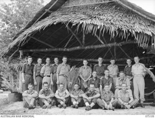 MILILAT, NEW GUINEA. 1944-08-07. OFFICERS OF HEADQUARTERS, 5TH DIVISION OUTSIDE THEIR THATCHED MESS. IDENTIFIED PERSONNEL ARE:- B259 CAPTAIN C. THOMPSON, SALVATION ARMY (1); NX146232 LIEUTENANT ..