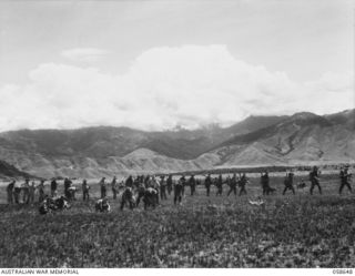 DUMPU, NEW GUINEA, 1943-10-05. "D" COMPANY, 2/16TH AUSTRALIAN INFANTRY BATTALION, WORKING ON A NEW AIRSTRIP AT DUMPU, WHILE A SECTION OF THE 2/27TH AUSTRALIAN INFANTRY BATTALION MOVES FORWARD