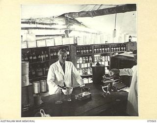 ORO BAY, NEW GUINEA. 1943-07. STAFF SERGEANT N.G. DOUGLAS WORKING IN THE DISPENSARY OF THE MAIN DRESSING STATION, 10TH FIELD AMBULANCE