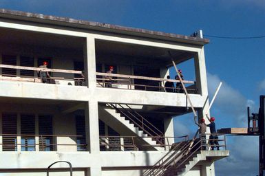 Members of the 200th and 201st Red Horse Air National Guard, Rickenbacker Air National Guard Base, Columbus, Ohio, move boards to the third floor of old dorms, at Andersen Air Force Base, Guam, that will be converted into temporary housing for victims of Typhoon Paka