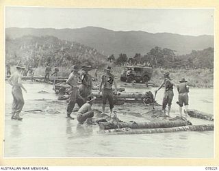 DANMAP RIVER, NEW GUINEA. 1945-01-06. TROOPS OF THE PIONEER PLATOON 2/8TH INFANTRY BATTALION BUILDING A TEMPORARY COCONUT LOG BRIDGE OVER A TRIBUTARY OF THE RIVER. THIS BRIDGE HAD TO BE BUILT IN ..