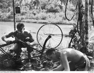 BOUGAINVILLE ISLAND. 1945-03-08. V507468 PRIVATE I. COOPER (1) AND NX155417 CORPORAL F. FEATHERBE (2), 25TH INFANTRY BATTALION, REPAIRING A JAPANESE BICYCLE WHICH THEY FOUND IN A DESERTED ENEMY ..