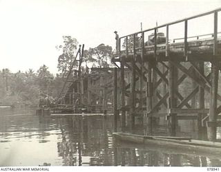 JACQUINOT BAY, NEW BRITAIN. 1945-02-09. A STRINGER FOR THE MAIN DECKING BEING MANOEUVRED ON TO THE NEW HIGH LEVEL BRIDGE BEING BUILT OVER THE KALUMALAGI RIVER BY TROOPS OF THE 13TH FIELD COMPANY