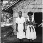 Man, woman and child in front of house