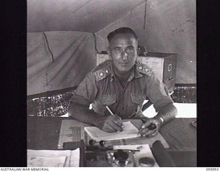 CAPE WOM, WEWAK AREA, NEW GUINEA. 1945-09-01. LIEUTENANT D.G. STEPHENS, ORDNANCE OFFICER, HEADQUARTERS 6 DIVISION, AT HIS DESK