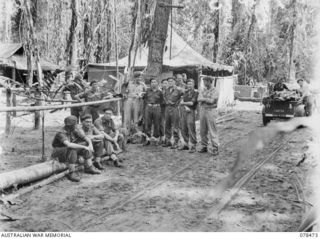 TAGESSI, BOUGAINVILLE ISLAND. 1945-01-17. OFFICERS AND NON COMMISSIONED OFFICERS OF THE MEDICAL DRESSING STATION, 7TH FIELD AMBULANCE IN FRONT OF THE UNIT ORDERLY ROOM. IDENTIFIED PERSONNEL ARE:- ..