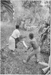 Returned laborers, purification ritual: returned laborer holds pig during sacrifice