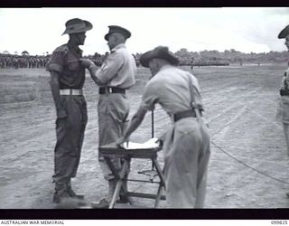 RABAUL, NEW BRITAIN, 1946-02-14. MAJOR GENERAL K.W EATHER, GENERAL OFFICER COMMANDING 11 DIVISION, PRESENTING THE MILITARY MEDAL TO LIEUTENANT A.E. BENNETT, 2 NEW GUINEA INFANTRY BATTALION, DURING ..