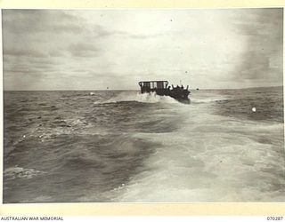 KELANOA AND BUTUBUTU, NEW GUINEA, 1944-02-08. A BARGE LOADED WITH TROOPS AND STORES OF HEADQUARTERS 5TH DIVISION SIGNALS, IN A ROUGH SEA BETWEEN KELANOA AND BUTUBUTU