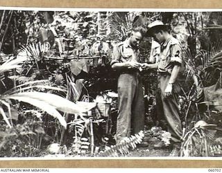 FINSCHHAFEN, NEW GUINEA. 1943-10-30. VX40358 REGIMENTAL AID POST LANCE SERGEANT J. H. CARTWRIGHT OF BRIGHTON, VIC (LEFT), OF HEADQUARTERS, 26TH AUSTRALIAN INFANTRY BRIGADE DRESSING THE HAND OF ..