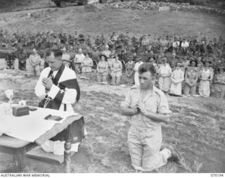 PORT MORESBY, NEW GUINEA. 1944-02-07. WX17091 CHAPLAIN C.W. CUNNINGHAM, MBE., (ROMAN CATHOLIC) (1) RECITING PRAYERS AT THE CONCLUSION OF REQUIEM MASS AT BOMANA WAR CEMETERY. NX45303 PRIVATE J.A. ..