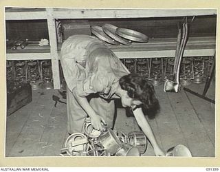 LAE, NEW GUINEA, 1945-05-06. STAFF-SERGEANT O.M.G. EDWARDS, COMPANY QUARTERMASTER SERGEANT, RETRIEVING DROPPED KETTLES AT THE AUSTRALIAN WOMEN'S ARMY SERVICE BARRACKS IN BUTIBUM ROAD. FINAL ..