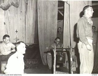 LAE AREA, NEW GUINEA. 1945-01-31. VX147884 PRIVATE FRED EDDY, SOLOIST (2) RENDERING AN ITEM DURING A CAMPFIRE CONCERT STAGED BY PERSONNEL OF THE 22ND WORKS COMPANY. IDENTIFIED PERSONNEL ARE:- ..