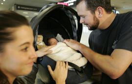 Denver residents Mike and Carie Fay care for baby Josiah as they wait for their luggage at DIA Wednesday afternoon January 18, 2006. They returned home from Hawaii today with Mike's sister, Sarah's, newborn baby, Josiah. Sarah was beaten nearly to death b