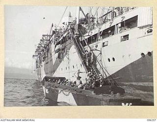 JACQUINOT BAY, NEW BRITAIN. 1945-09-09. MEMBERS OF 4 INFANTRY BRIGADE FILING UP THE GANGWAY OF HMAS MANOORA. THE MANOORA CARRIED TROOPS FOR THE OCCUPATION OF THE RABAUL AREA FOLLOWING THE SURRENDER ..