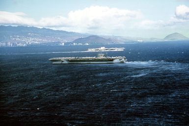 Aerial port beam view of the nuclear-powered aircraft carrier USS CARL VINSON (CVN 70) entering port. In the background another aircraft carrier is departing port