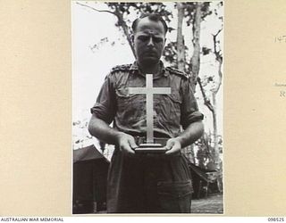 CAPE PUS, NEW GUINEA. 1945-11-03. CHAPLAIN N.D. WINN, 2/2 INFANTRY BATTALION, HOLDING A CROSS CONSTRUCTED FROM THE PROPELLER BLADE OF A JAPANESE ZERO AIRCRAFT SHOT DOWN DURING THE AITAPE-WEWAK ..