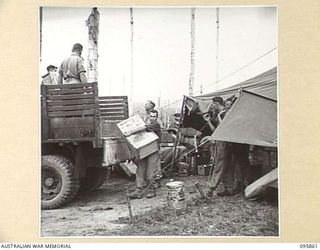 BORAM BEACH, WEWAK AREA, NEW GUINEA. 1945-08-31. SERGEANT G.H. RACE, 2/41 LIGHT AID DETACHMENT, CORPS OF AUSTRALIAN ELECTRICAL AND MECHANICAL ENGINEERS, UNLOADING BOXES FROM A TRUCK