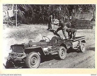 PARCHY RIVER, NEW GUINEA, 1945-07-23. TROOPS OF 2/14 FIELD COMPANY, ROYAL AUSTRALIAN ENGINEERS, LOADING MORTAR BOMBS ON TO A JEEP TRAILER AT THE JEEP HEAD