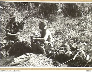 GOODVIEW, NEW GUINEA, 1943-08-07. VX35961 PRIVATE R. PERRY (1) AND VX4286 PRIVATE A. E. ROADLEY (2), BOTH OF THE 2/5TH BATTALION ENJOY THE SUN OUTSIDE THEIR GUN PIT