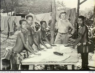 KIRIWINA, TROBRIAND ISLANDS, PAPUA. C. 1944-03. RAAF AIRMAN SUPERVISING LOCAL PAPUAN NATIVE WOMEN, JILL TOOTS, MATILDA AND JOSEPHINE, SCRUBBING THE WASHING ON A TABLE AT NO. 46 OPERATIONAL BASE ..