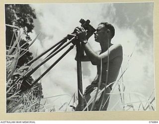 LAE AREA, NEW GUINEA. 1944-11-15. NX143630 STAFF SERGEANT L.F. WILSON, 2/7TH ADVANCED WORKSHOPS GIVING A FINAL CHECK TO A THEODOLITE WHICH HE HAS JUST FINISHED REPAIRING