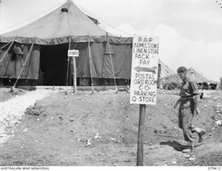 WUNUNG PLANTATION, JACQUINOT BAY, NEW BRITAIN. 1945-03-02. A DIRECTION SIGNPOST OUTSIDE THE X-RAY TENT OF THE 105TH CASUALTY CLEARING STATION. SEEN IS:- VX75858 CORPORAL E.J. GOWER