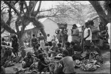 Group of people with a European style building in the background, Boong, native market, Rabaul, New Guinea, ca. 1929 / Sarah Chinnery