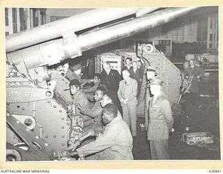 MARIBYRNONG, AUSTRALIA. 1942-10-12. SIX NATIVE SOLDIERS FROM NEW GUINEA WHO WERE SHOWN OVER THE MUNITION WORKS AT MARIBYRNONG ARE SEEN BORE EXAMINING THE MOUNTING OF A BIG GUN