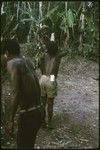 Pig festival: boy drinks bespelled water from bamboo tube held by elder