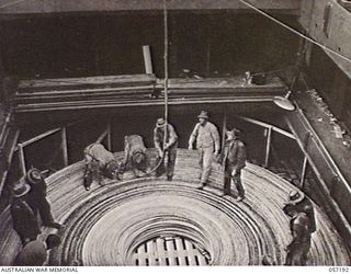 MELBOURNE, VIC. 1943-09-01. COILING DOWN A SUBMARINE CABLE INTO THE HOLD OF THE SS. MERNOO, MARINE CABLE LAYING SHIP, IN PREPARATION FOR LAYING THE CABLE FROM CAPE YORK, NORTH QUEENSLAND TO PORT ..