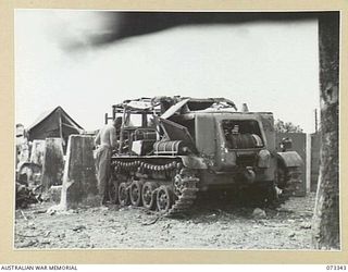 MADANG, NEW GUINEA. 1944-05-18. A MEMBER OF THE 55TH FIELD PARK COMPANY EXAMINING AN ABANDONED JAPANESE TRACKED VEHICLE. IT IS ONE OF MANY DIESEL POWERED VEHICLES LOCATED IN THE AREA