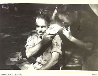 KELANOA, NEW GUINEA, 1944-02-21. Q100403 CORPORAL W. NEWBERRY (1) THE REGIMENTAL AID POST CORPORAL, SYRINGING THE EAR OF QX37976 SERGEANT A.E. SMITH (2) AT THE 5TH AUSTRALIAN DIVISION HEADQUARTERS, ..