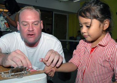 U.S. Navy PETTY Officer 1ST Class Daniel Jones, a Sailor assigned to Naval Computer Telecommunications Station (NCTS) Guam, fingerprints Alexis Kosak, during the 11th annual Project KidCare event held at the Agana Shopping Center. The project's goal is to assist local authorities with locating and recovering missing children and inform the public about ways to prevent child abduction. (U.S. Navy PHOTO by Mass Communication SPECIALIST 2nd Class John F. Looney) (Released)