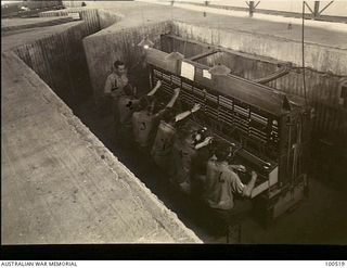 Lae, New Guinea. 1944-06-18. Lieutenant S. G. Tomkins supervising operators of 23 Wireless Telegraphy Section (Heavy) working on the unit switchboard in the bomb blast shelters. Left to right: ..
