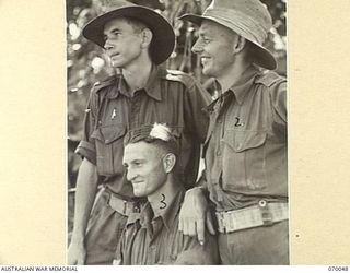 Informal portrait of three members of the 2/15th Battalion who recently received decorations, at Kelanoa, New Guinea. QX5802 Corporal Robert Cunninghame Norris, Military Medal (MM) (1); QX8529 ..