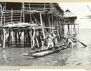 PORT MORESBY, PAPUA. 1942-07-20. AUSTRALIAN INFANTRYMEN RETURNING FROM A PATROL IN A NATIVE CANOE, A PRIMITIVE BUT EFFECTIVE WAY OF PATROLLING THE BEACHES. NOTE THE LARGE SWEEP CAR USED BY THE MAN ..
