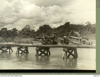 Puriata River, Bougainville Island. 1945-04-03. A tractor of 15th Field Company, Royal Australian Engineers, towing a carryall across the old McKinna Bridge. The carryall was used for top dressing ..